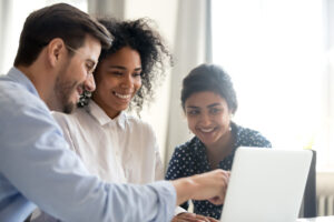 Diverse happy interns listening to mentor explaining online project